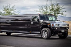 Black Hummer H2 Super Stretch limousine with tinted windows parked on the street