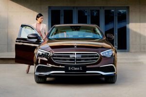Front view of a luxury Mercedes-Benz E-Class sedan with a woman opening the door