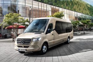 Beige Mercedes-Benz Sprinter parked in a modern urban setting with large glass buildings