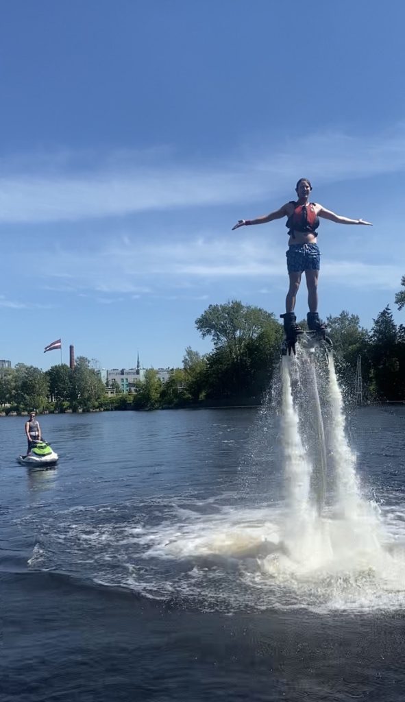 Flyboarder floating above water with arms outstretched