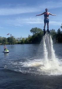 Flyboarder floating above water with arms outstretched