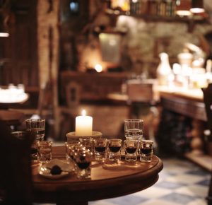 Candle-lit table with balsam shot glasses in a rustic cellar