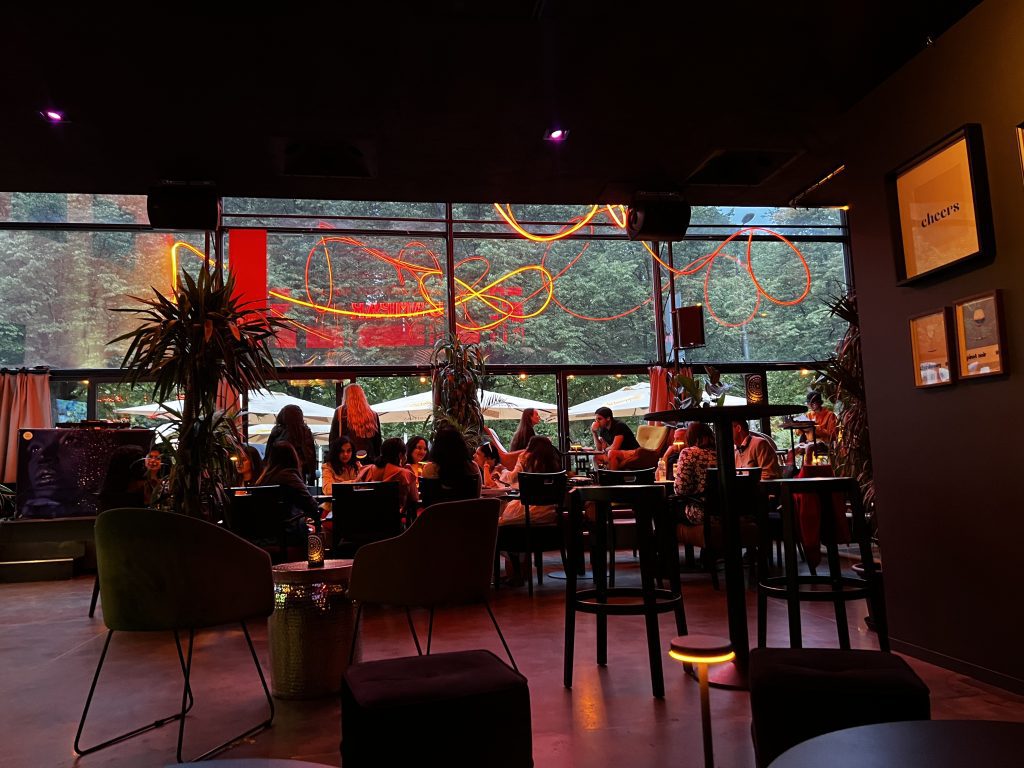 Neon-lit modern lounge bar with people enjoying dinner.
