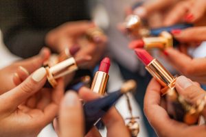 Group of women holding lipstick tubes in various shades