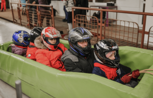 Family group inside a green soft bobsleigh sled on the start line