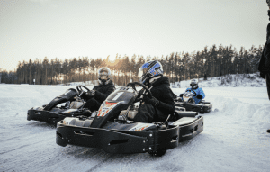 People racing go-karts on a snow-covered track at sunset