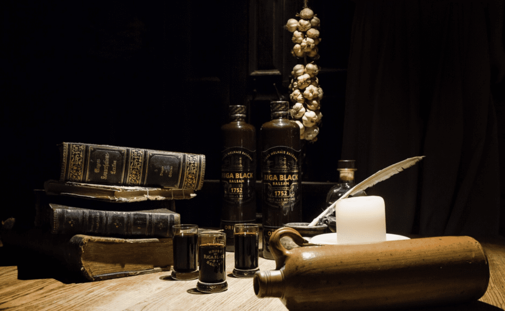Riga Black Balsam bottles next to vintage books, garlic, and a candle