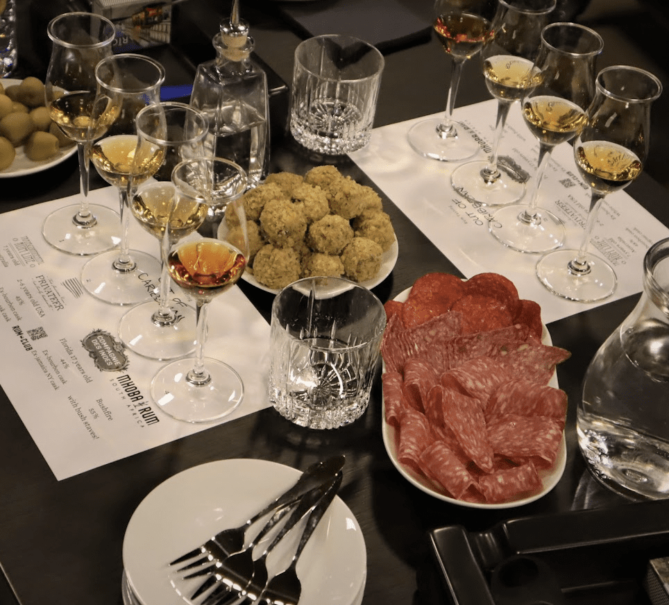 Tasting table with rum glasses, cold cuts, and gourmet snacks
