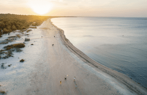 Plage de sable au coucher de soleil avec des promeneurs.