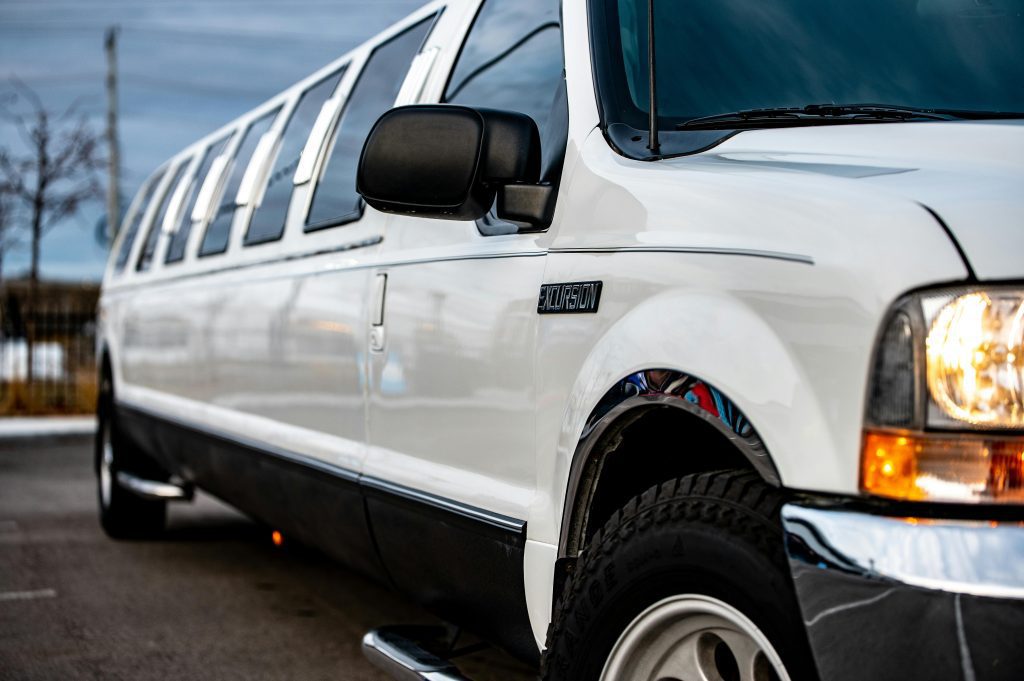 White stretch SUV limousine parked outside under cloudy sky.