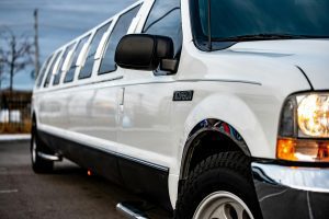 White stretch SUV limousine parked outside under cloudy sky.