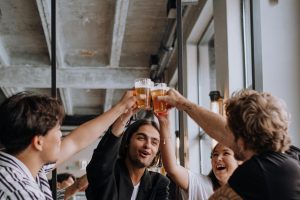 Friends cheering with pints of beer at a modern bar.
