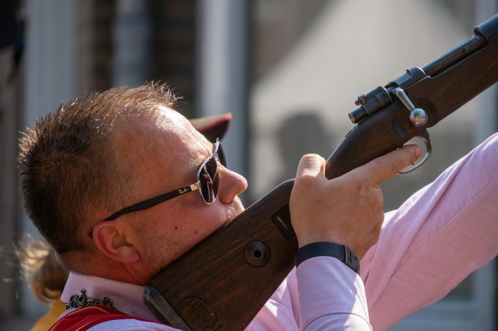Man aiming a rifle upwards during a shooting activity.