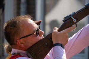 Man aiming a rifle upwards during a shooting activity.