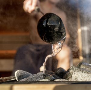 Pouring water on hot sauna stones to create steam