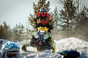 Snowmobile rider catching air during a jump in the snow