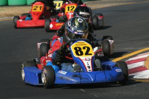 Close-up of a go-kart driver leading a group of racers on an outdoor track