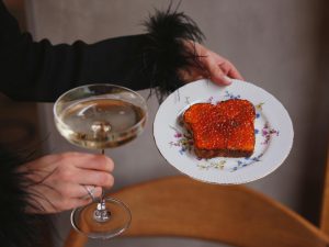Hand holding a plate with caviar toast and a coupe of champagne