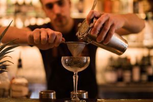 Bartender pouring cocktail through a strainer at a Riga bar