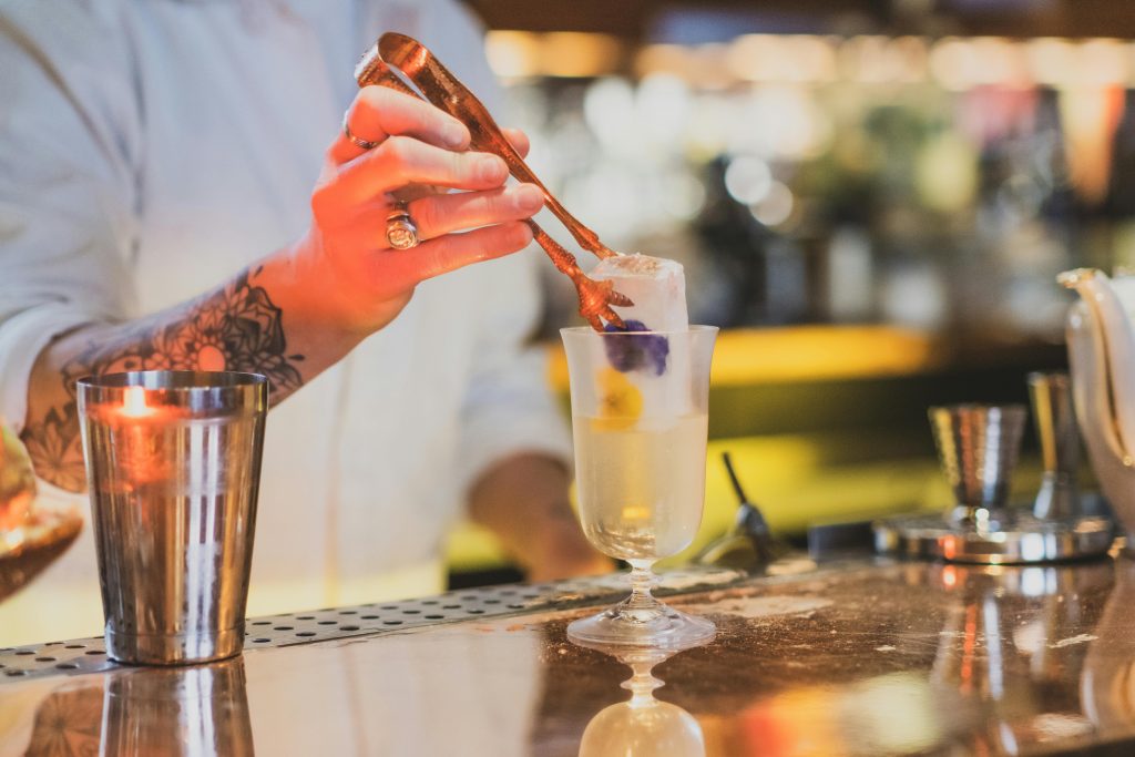 Bartender placing ice cube into a cocktail glass