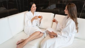 Two women in white robes enjoying herbal tea in a spa lounge